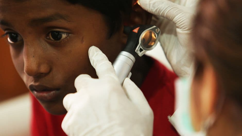 A young boy undergoes a routine ear examination by a medical professional using an otoscope.