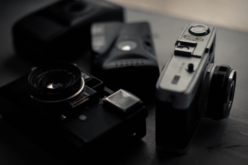 From above of assorted professional retro photo cameras on wooden table in dark room