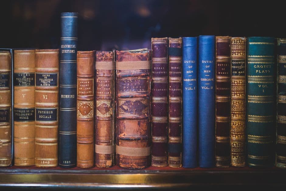 A collection of classic, leather-bound books neatly arranged on a wooden bookshelf.