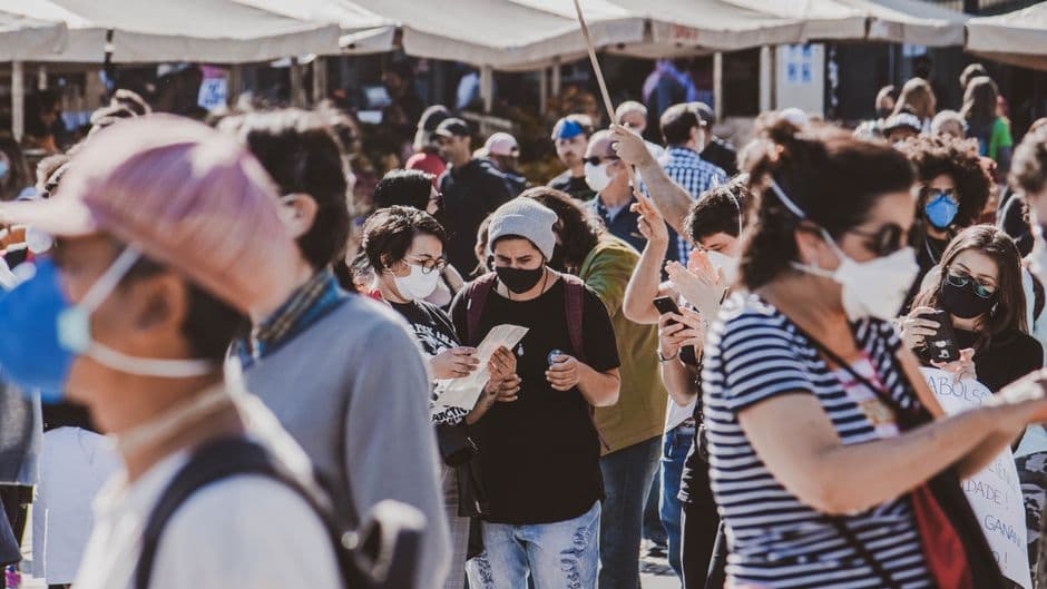 A diverse group of people wearing masks in an outdoor urban setting, highlighting community and safety.
