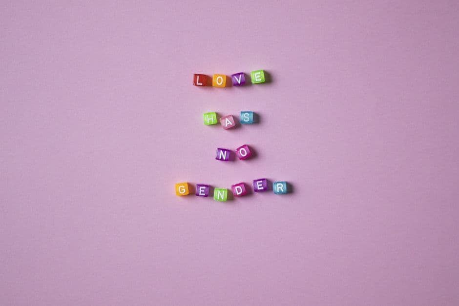 Colorful beads spelling 'Love Has No Gender' on a pink background, emphasizing inclusivity.