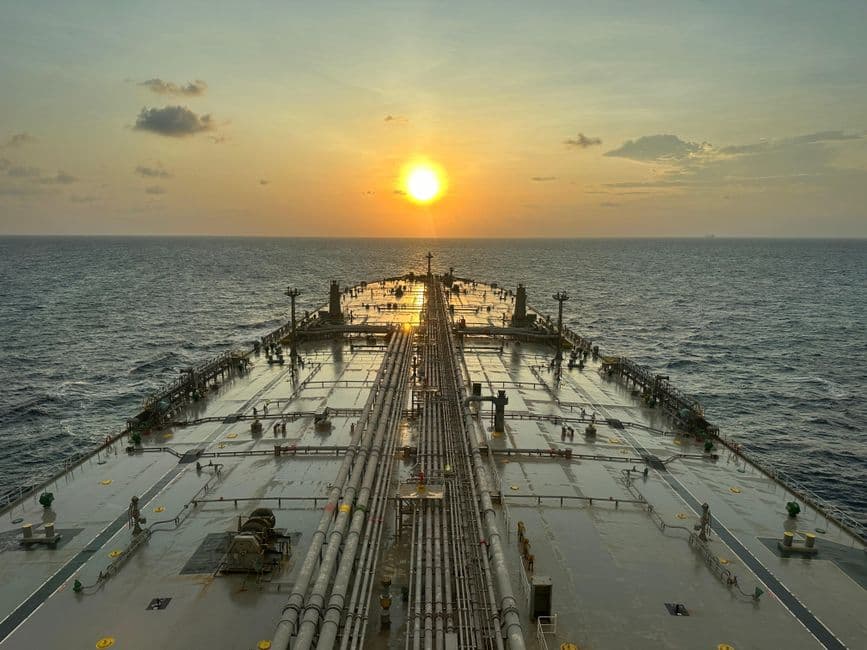 A large oil tanker sailing on the ocean with a sunset view.