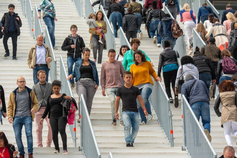A diverse crowd of people walking downstairs in a bustling urban environment, showcasing everyday life.