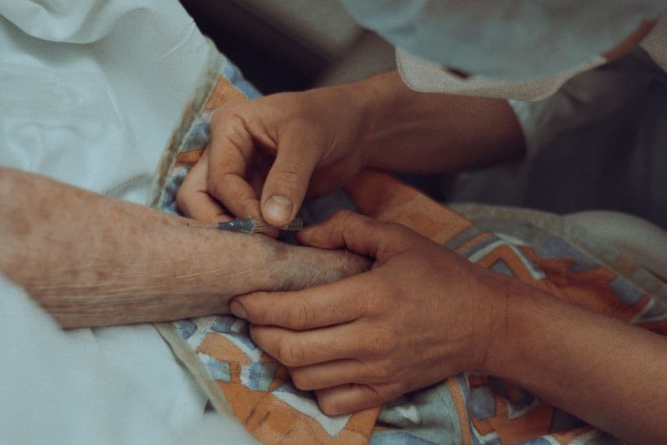 A healthcare professional administers an injection to an elderly patient in a hospital setting.