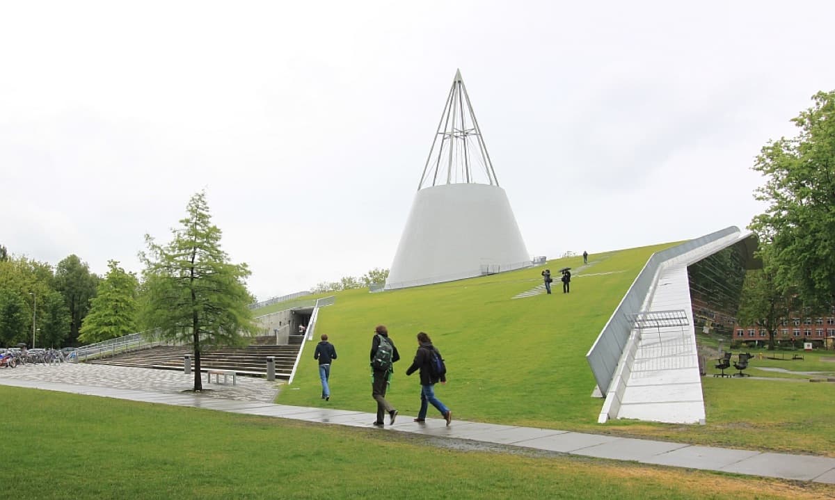 The distinctive green-roofed Library building of TU Delft featuring the iconic cone-shaped structure and landscape setting.