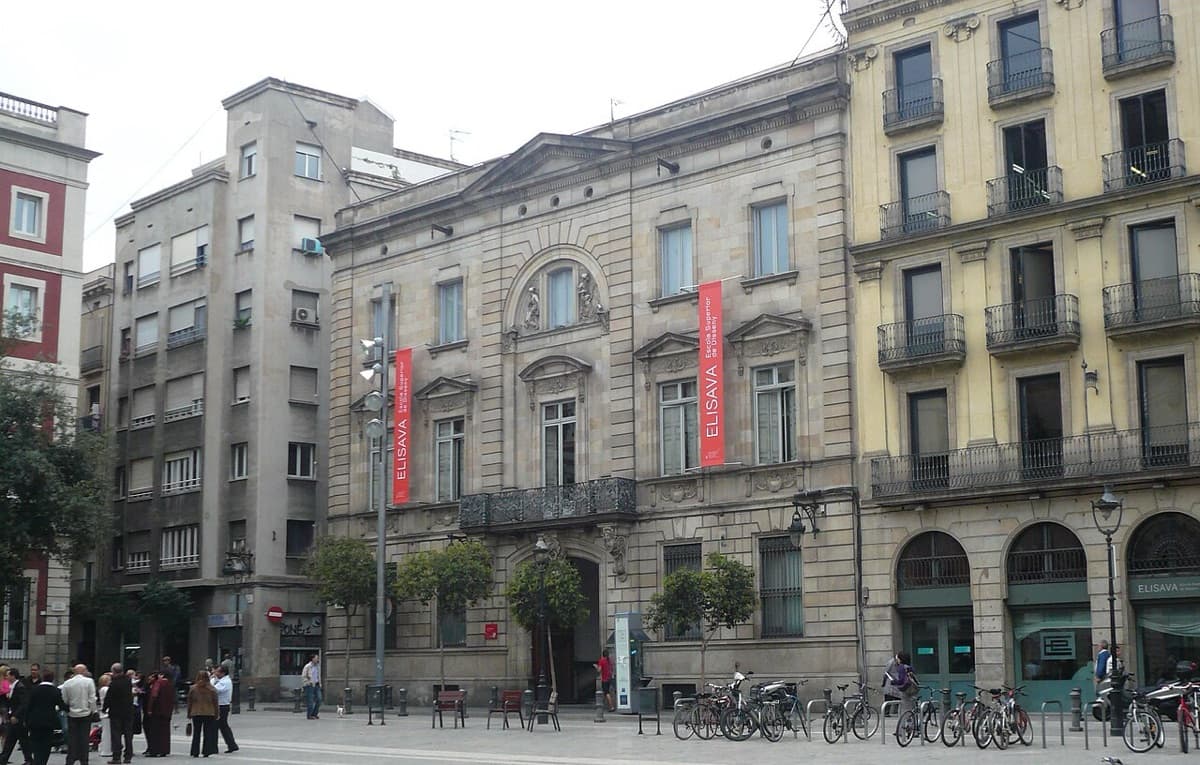 Historic institutional building housing Elisava Barcelona School of Design and Engineering at plaça de la Mercè, with red ELISAVA banners on ornate facade.