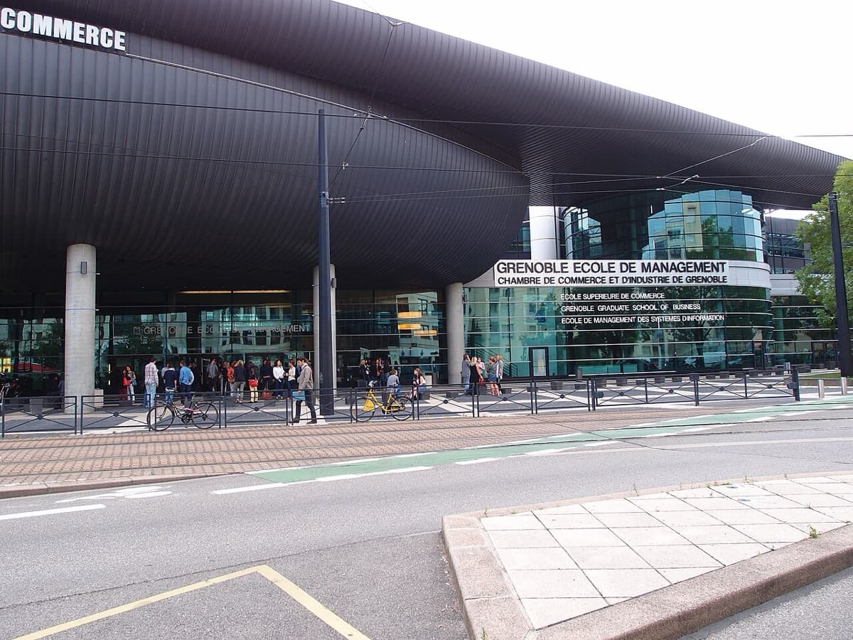 Grenoble Ecole de Management campus building showing 'GRENOBLE ECOLE DE MANAGEMENT' signage with modern architecture and plaza entrance.