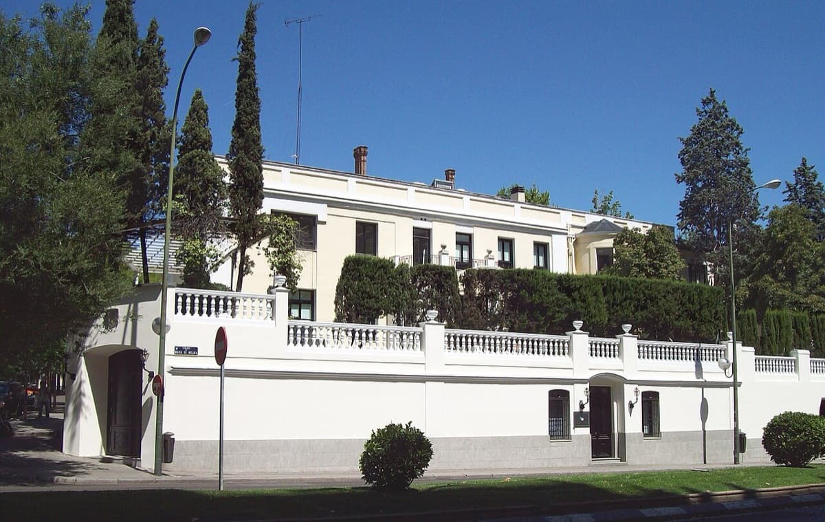 Elegant white classical building of IE Business School on Madrid street with ornamental railings.