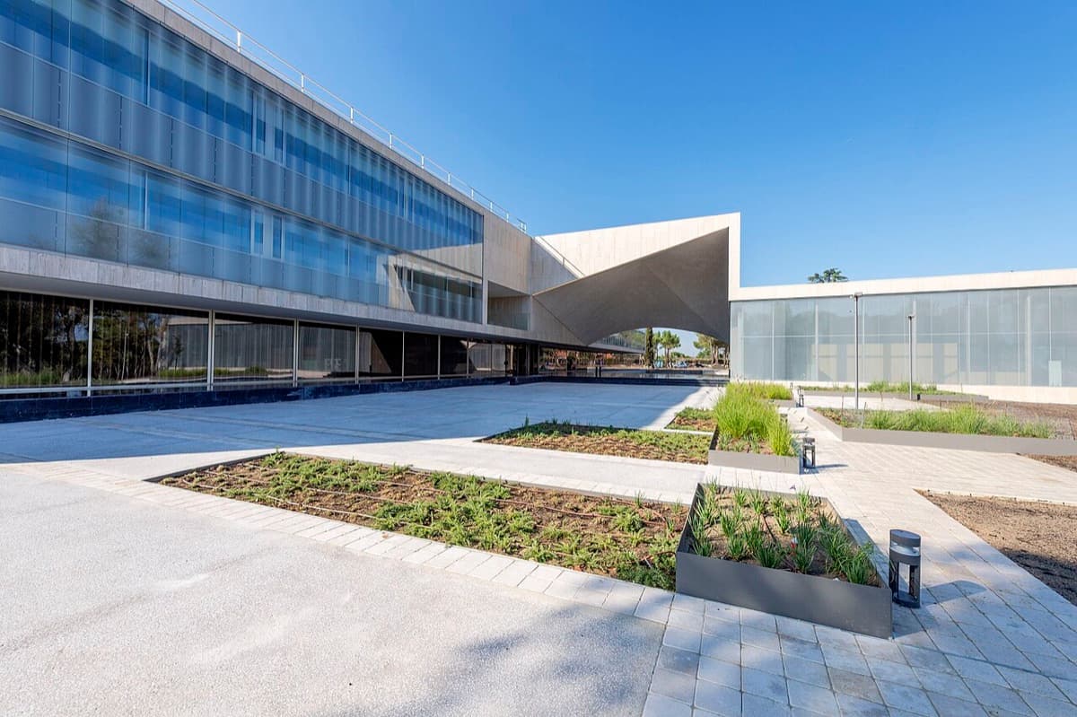 Modern IESE Business School building with blue glass facade and concrete panels.