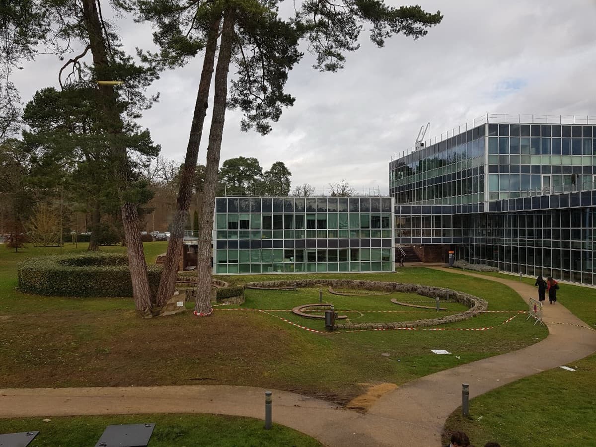 INSEAD Fontainebleau campus showing modern building architecture overlooking landscaped gardens with trees and lawn.
