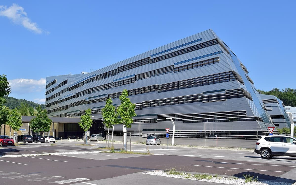 Modern glass and stone science park building of Johannes Kepler University Linz, featuring clean contemporary architecture with geometric facade elements in daylight.