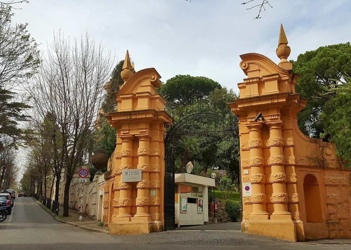 The ornate golden stone gate towers at the entrance to LUISS Guido Carli with distinctive architectural details and institutional signage.