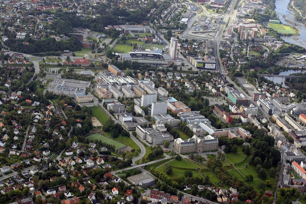An aerial view of NTNU's Gløshaugen campus in Trondheim, its buildings set among green space above the city.