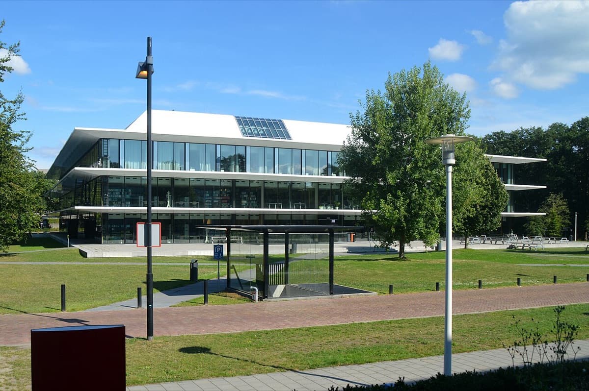 The glass-fronted Grotius building of the Faculty of Law at Radboud University, seen across its lawn under a clear sky.