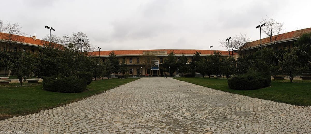 Universidad Carlos III campus quad with historic red-brick and stone buildings and wide paved plaza.