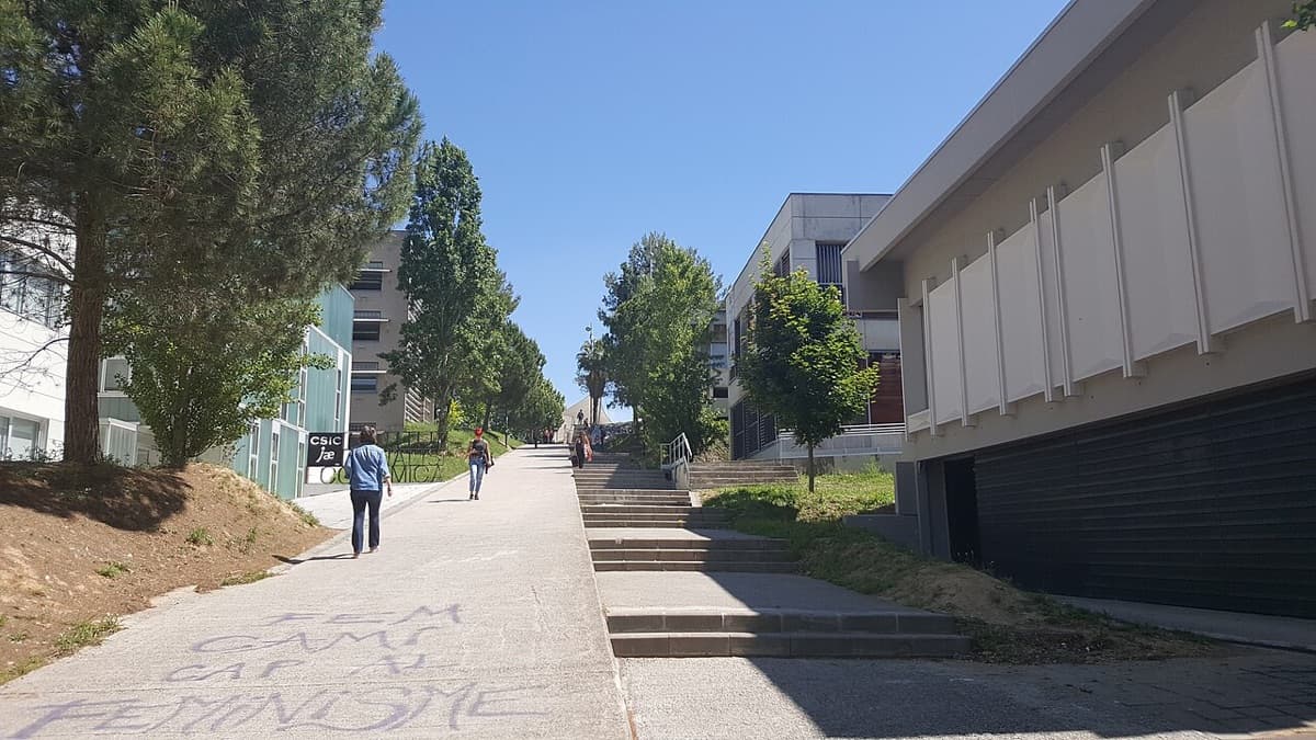 Universitat Autònoma de Barcelona campus walkway with modern buildings and landscaping.