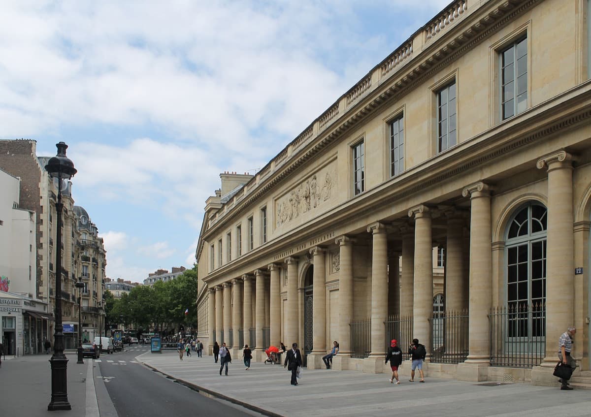 Historic Parisian university building with classical columns and courtyard entrance, showing neoclassical institutional architecture.