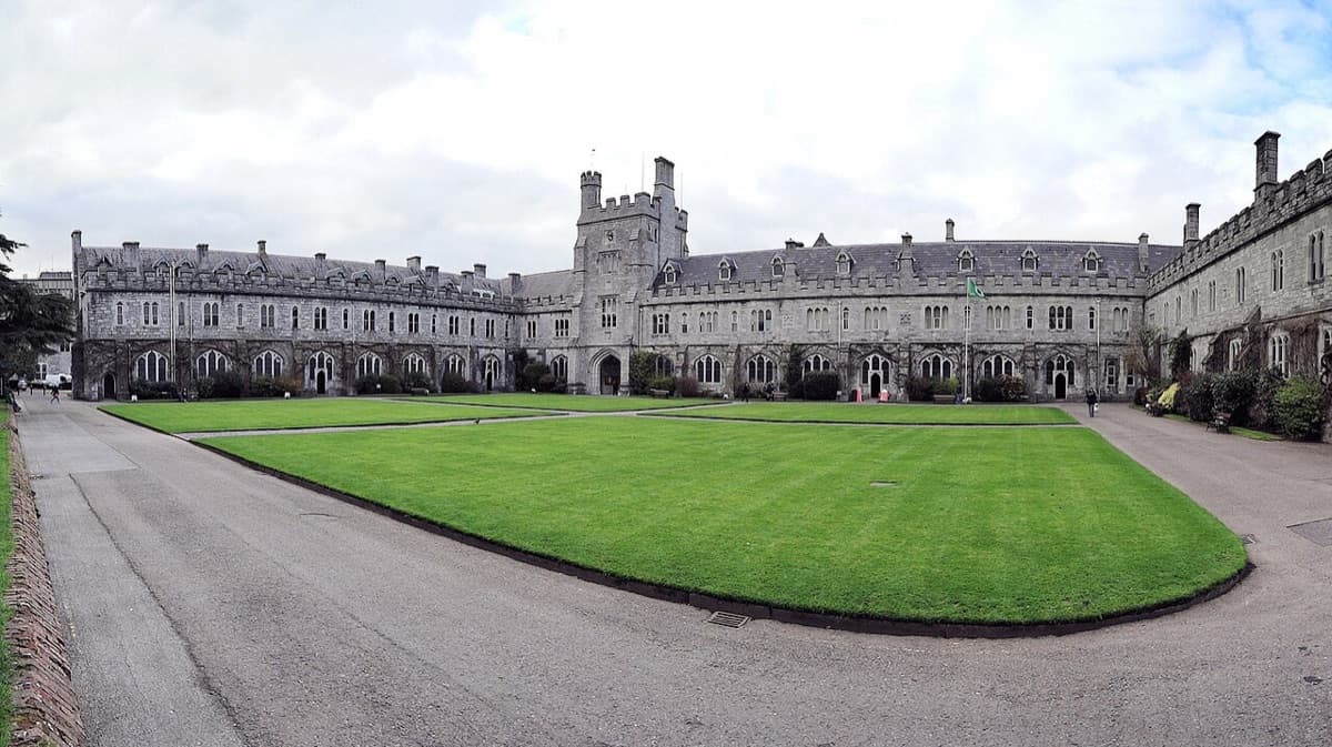 University College Cork historic quadrangle showing stone buildings across manicured green lawn.