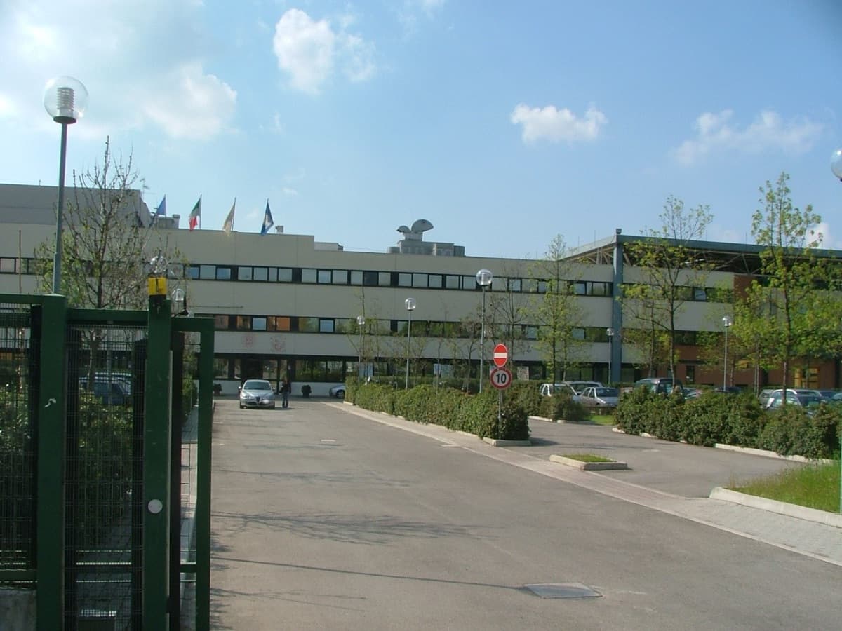 A modern faculty building of the University of Bologna showing contemporary campus architecture with outdoor parking area.