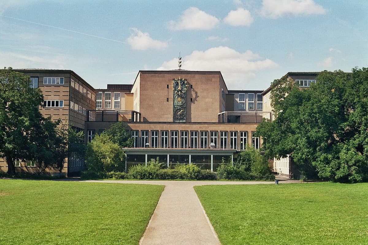 Main building of University of Cologne with lawn and walkway approach.