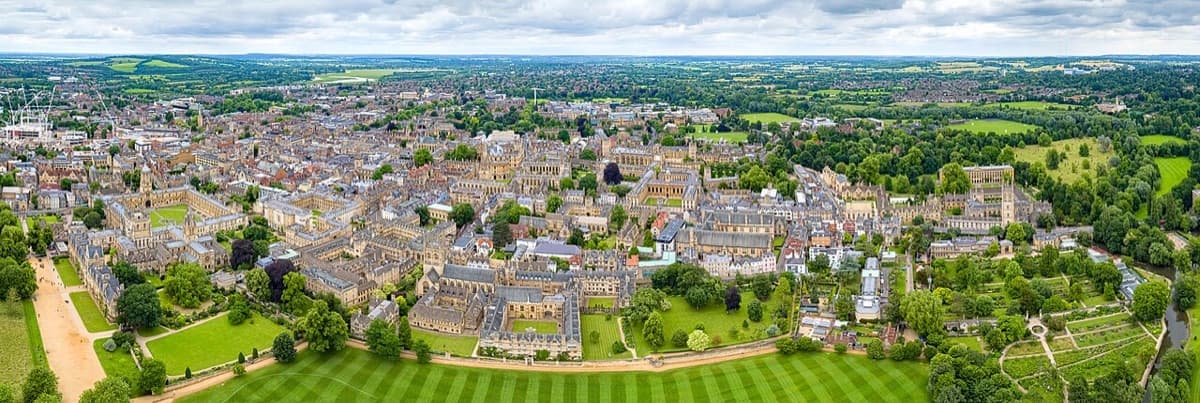 Aerial panorama of Oxford showing University of Oxford buildings and the surrounding city landscape in daylight.
