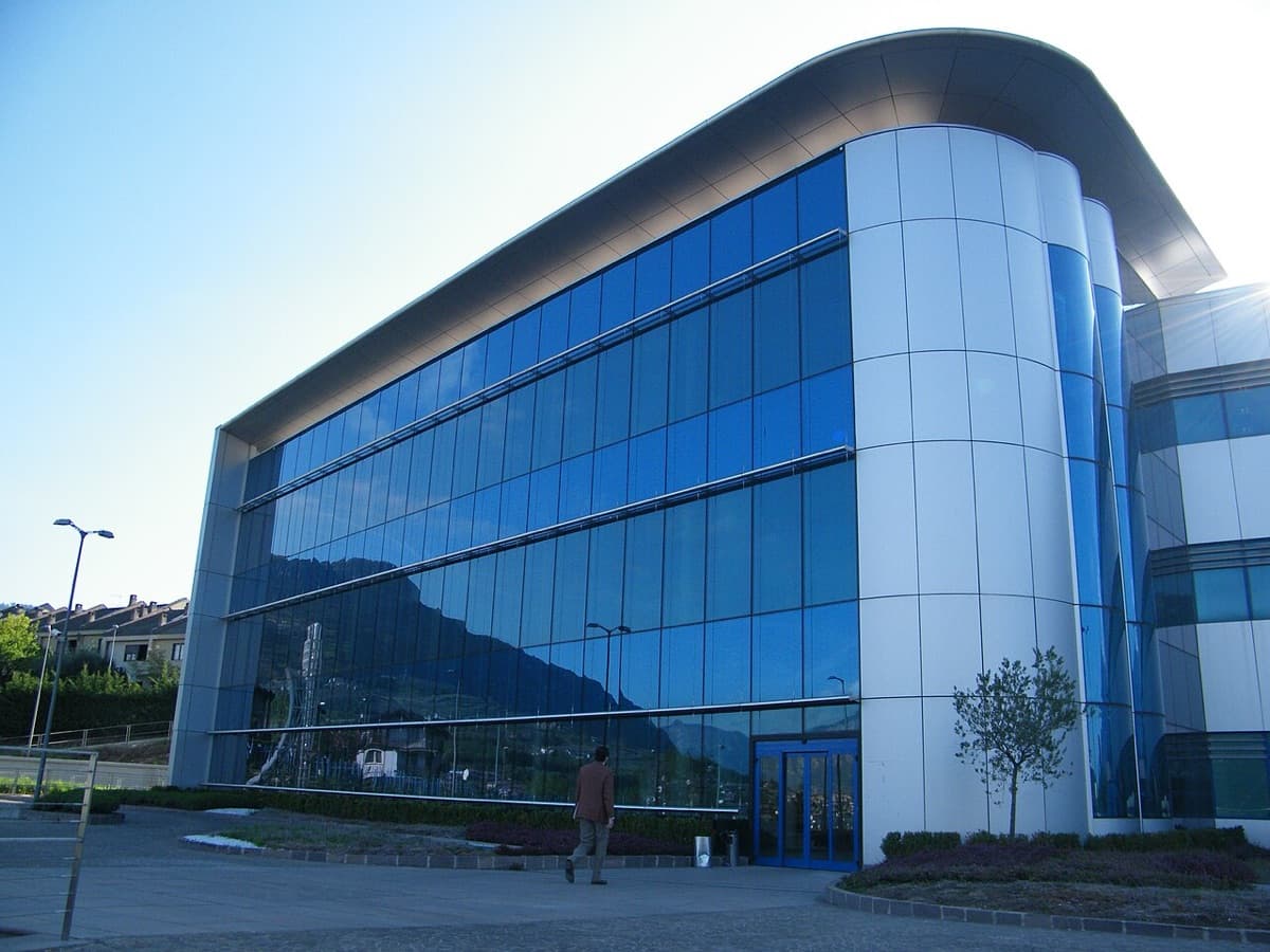 Modern curved glass and white facade campus building of University of Trento with architectural distinction and daylight exposure.