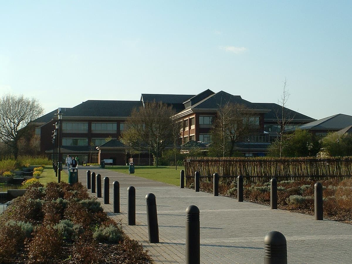 University of Warwick residential building set among landscaped grounds with trees and modern architecture.
